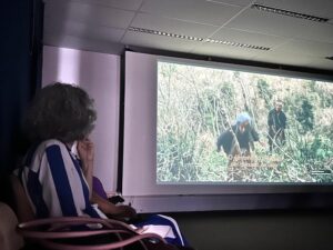 Idosa assiste a filme na tela grande.